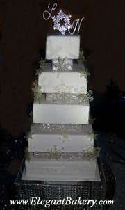 Square and elegantly tiered wedding cake is separated with pillars and has a large silver snowflake topper